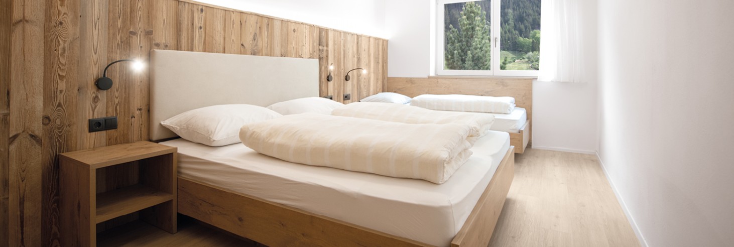 miramor: Appartamenti nuovissimi e intelligenti secondo gli standard più moderni Camera matrimoniale modernamente arredata con mobili in legno e un letto singolo