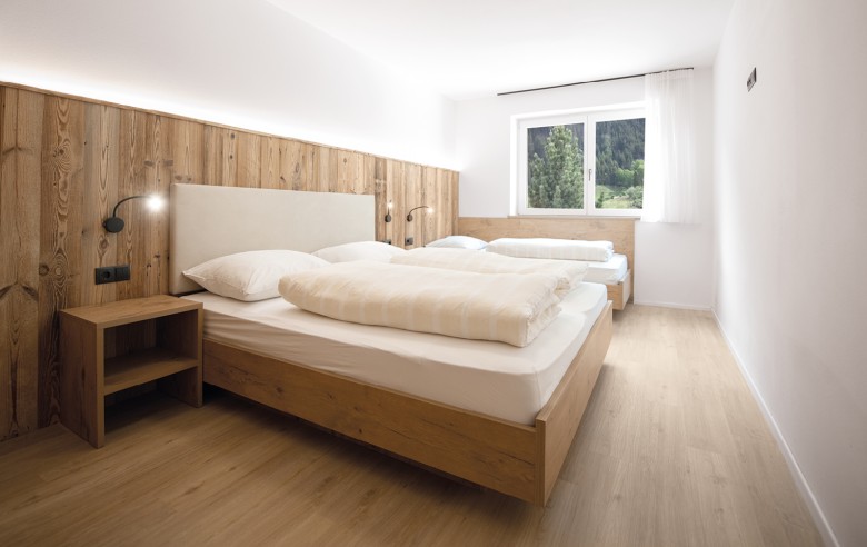 Camera matrimoniale modernamente arredata con mobili in legno e un letto singolo