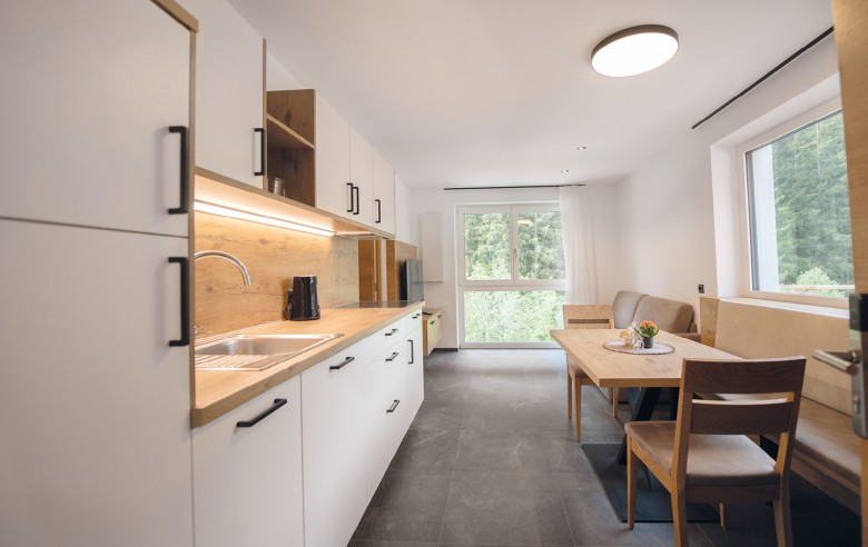 Cucina-soggiorno con moderno angolo cottura, comodo divano e tavolo da pranzo