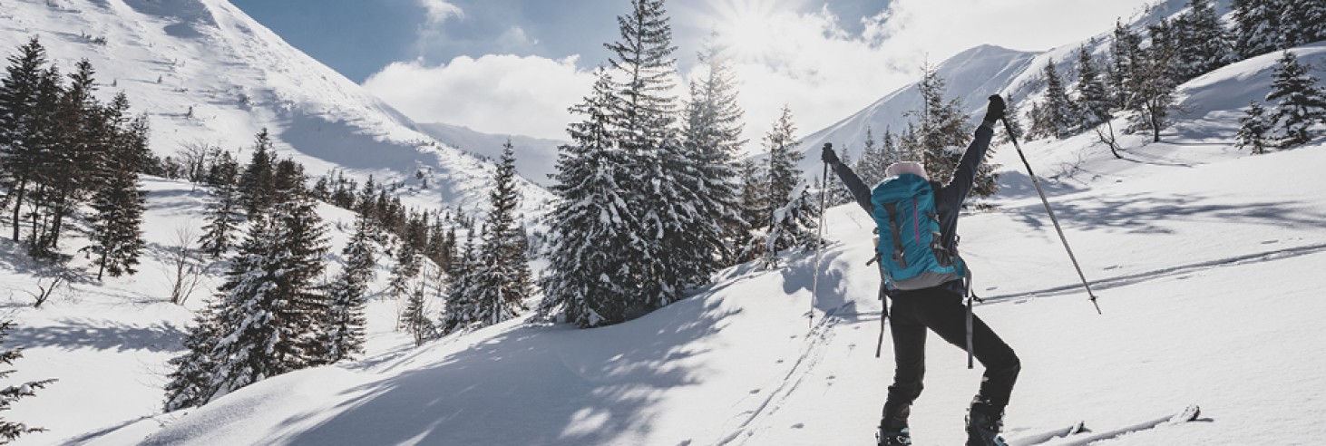 Skitourengeher mit Wanderrucksack und Skistöcken in einer verschneiten Berglandschaft in Südtirol