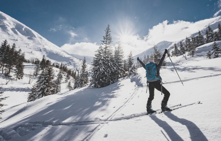 Sciatori alpinisti con zaino da trekking e bastoncini da sci in un paesaggio montano innevato in Alto Adige