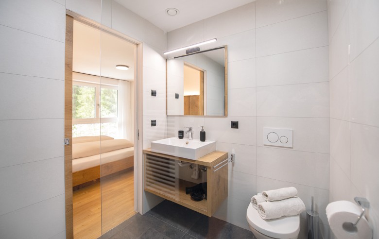 Bagno moderno con piastrelle eleganti, una doccia spaziosa, un lavabo e un'illuminazione elegante