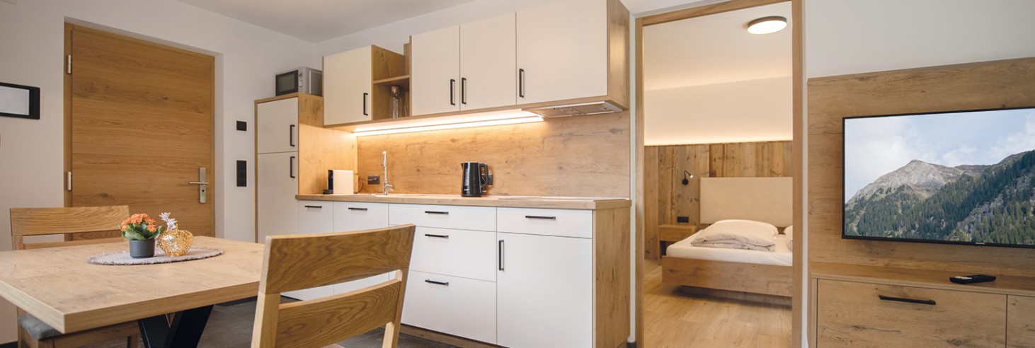 miramor: Atmosfera rilassata nella cucina di Racines Vista della cucina-soggiorno con tavolo da pranzo e divano e vista della stanza